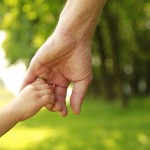 a parent holds the hand of a small child